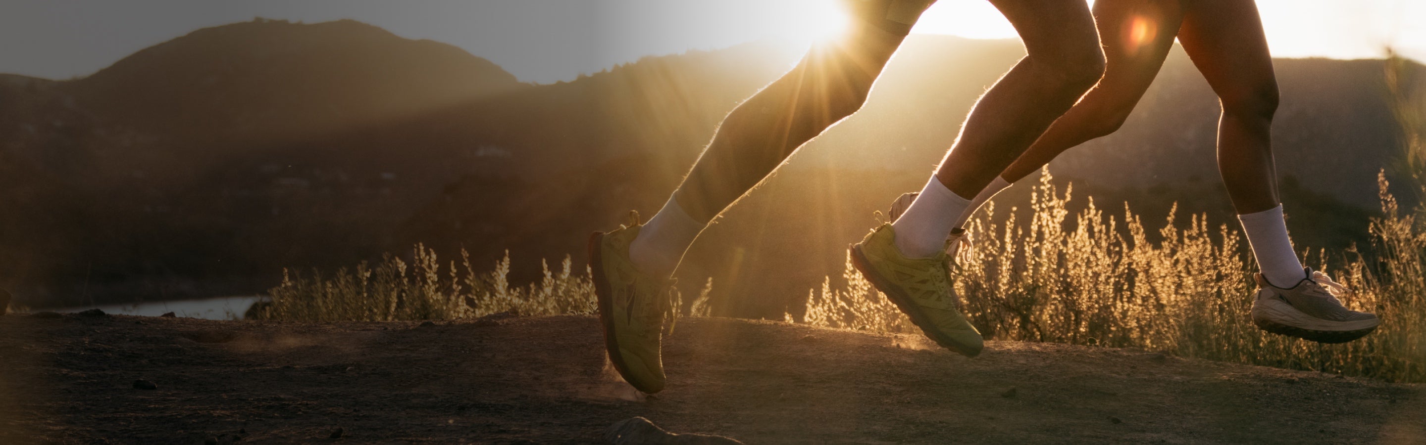 A pair of runners out on trail at sunset wearing matching white Darn Tough running socks