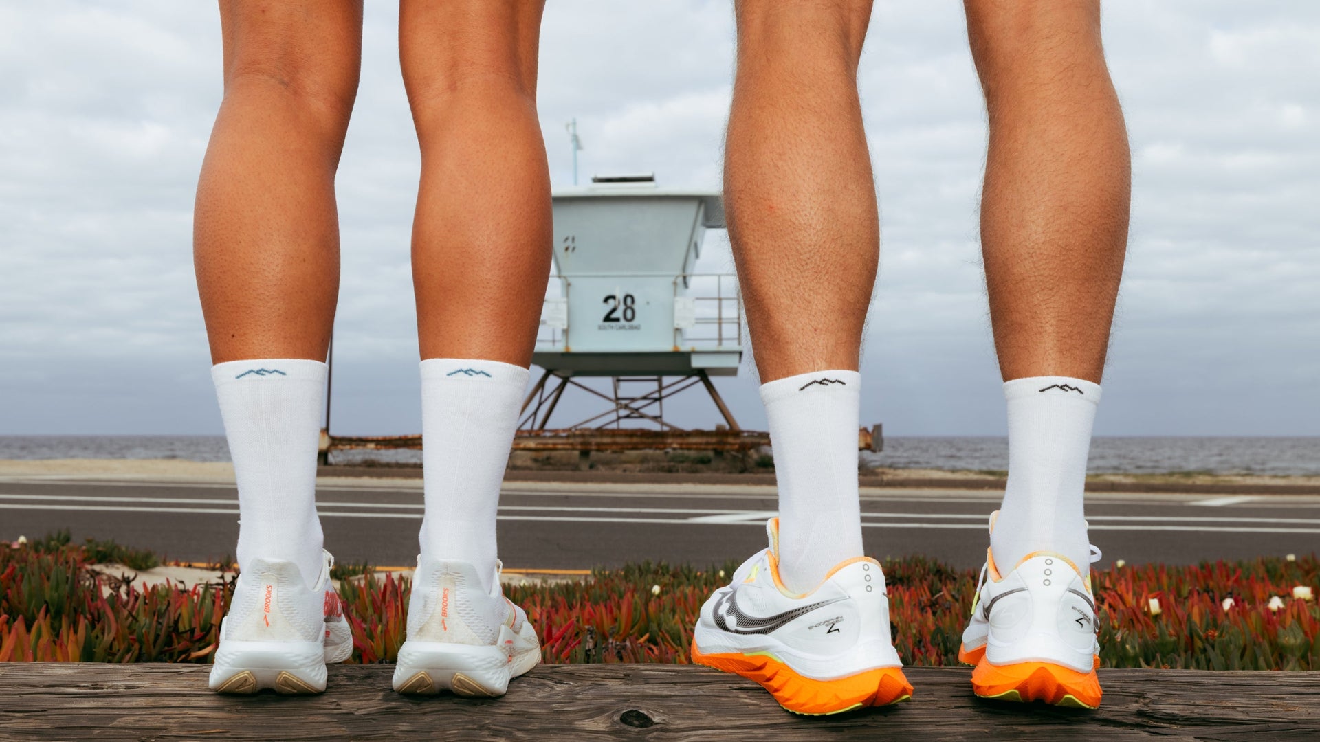 Two models standing in front of beach wearing the men and womens micro crew running sock in white