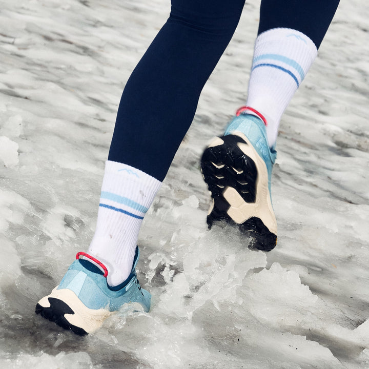 close up image of model in black leggings running through slush wearing 1114 element micro crew lightweight with cushion vapor white sock
