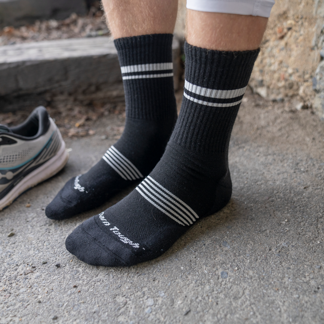 Model's feet on cement ground wearing the 1118 element micro crew in black with white striping and logo