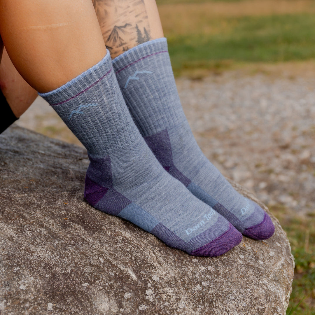 models feet on rock wearing the 1093 light denim featuring purple toe/heel and light blue body