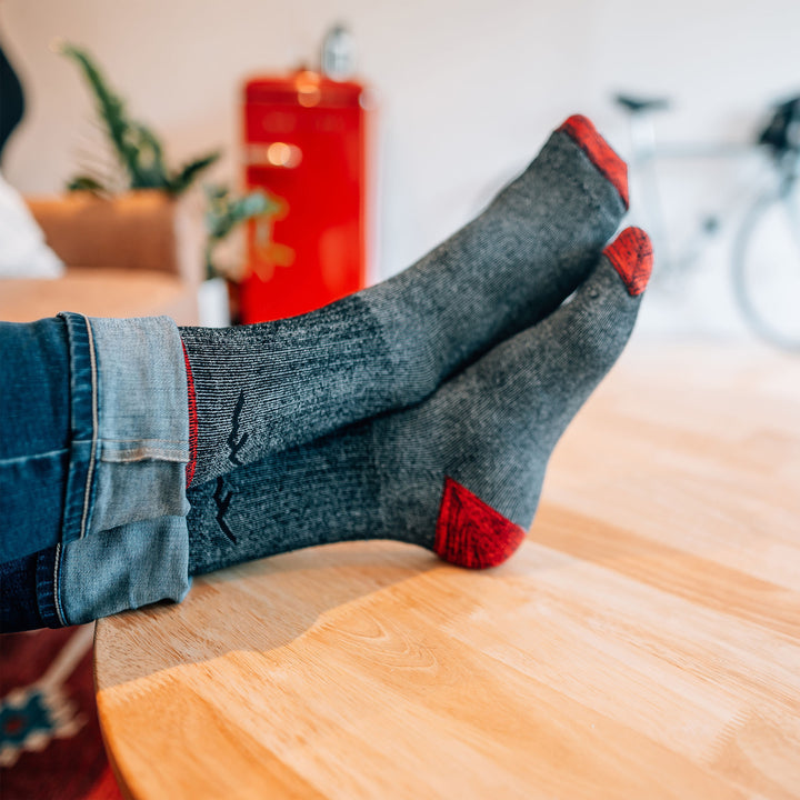 Model with hiis feet up on a coffee table wearing the men's mountaineering micro crew hiking sock in smoke