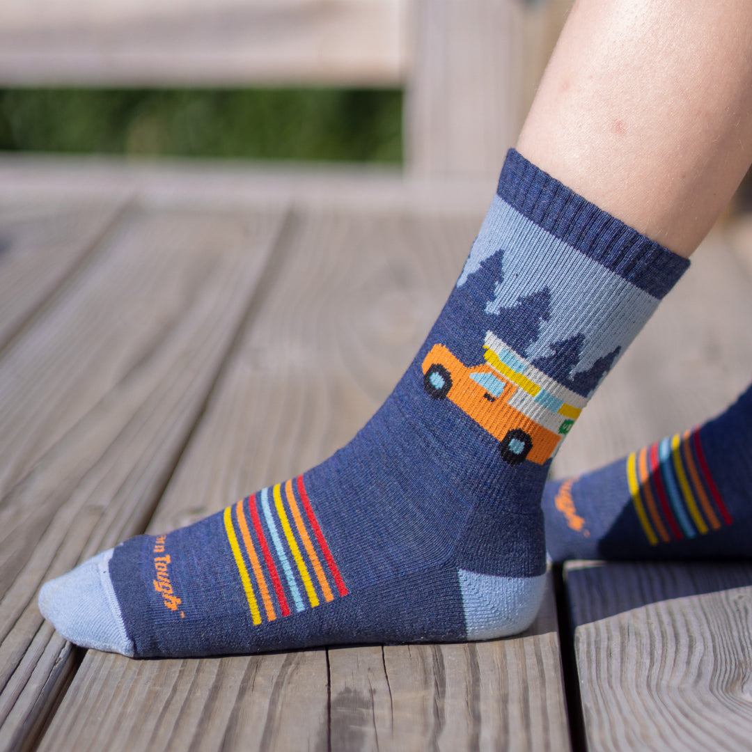 Side shot of model siitting outside wearing the juniors van wild micro crew hiking sock in denim blue
