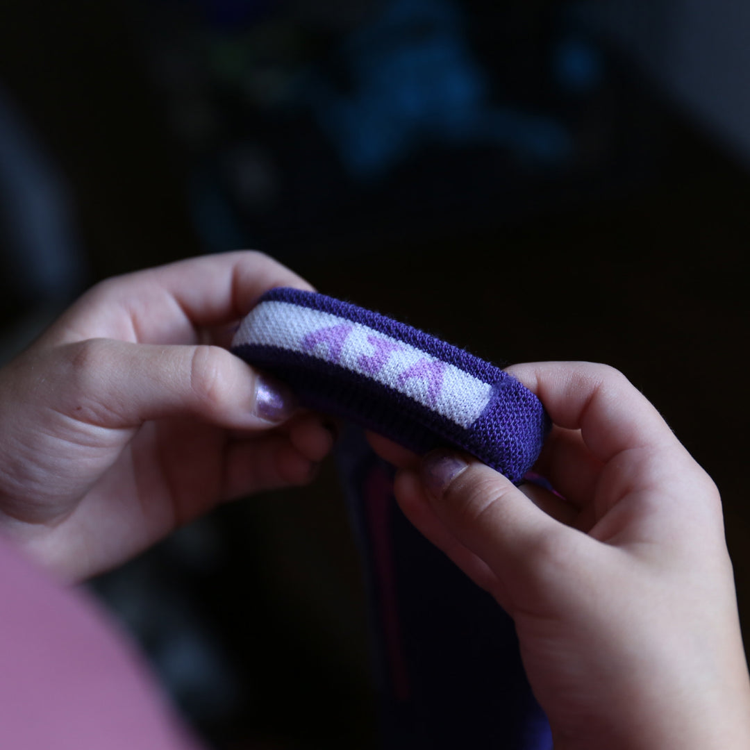 models hand holding the cuff of the 3810 T-bar over the calf ski and snowboard sock in grape colorway, features the Name tag area in cuff