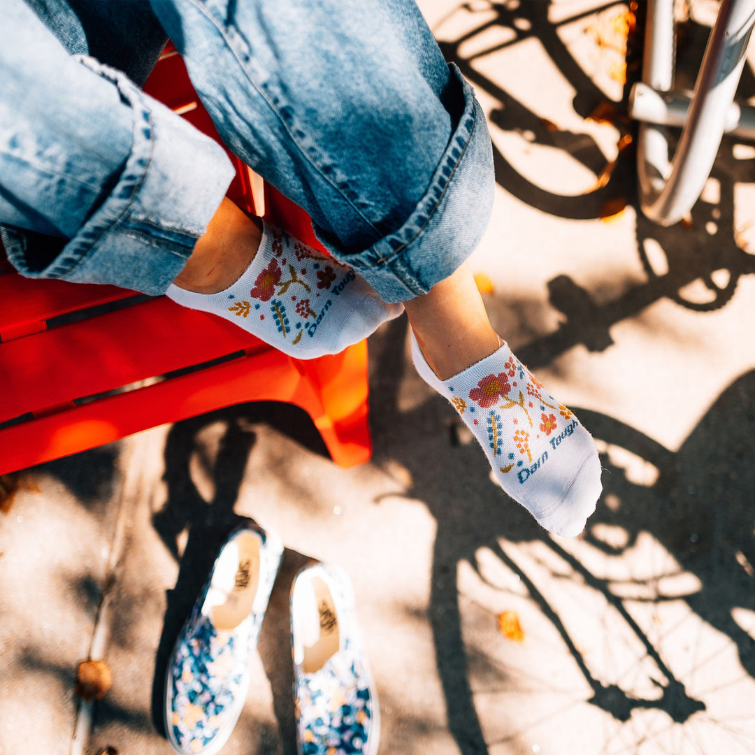 Overhead shot of model sitting on a red bench wearing the women's garden party no show hidden lifestyle sock in white