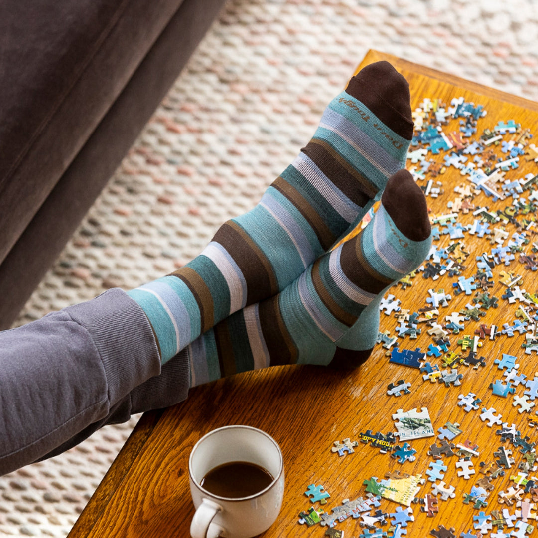 image of mans feet crossed and resting on coffee table with puzzle wearing 6090 druid crew lightweight aqua sock