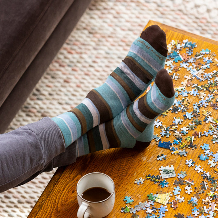 image of mans feet crossed and resting on coffee table with puzzle wearing 6090 druid crew lightweight aqua sock