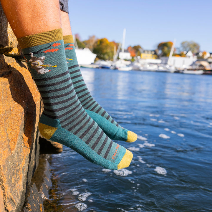 image of mans feet hanging over rock wall above water wearing 6096 wildlife crew lightweight with cushion fox teal sock