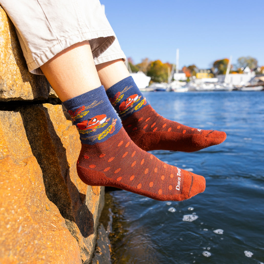 close up of womans feet hanging off rock wall over water wearing 6105 wild life crew lightweight with cushion fox foliage sock