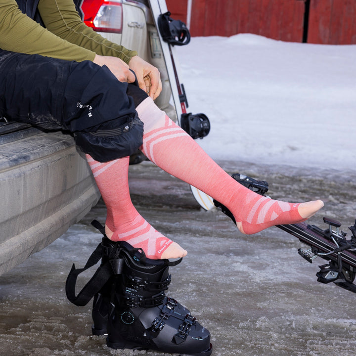 model sitting on edge of car trunk putting on ski boots wearing 8035 peaks RFL OTC ultra lightweight ski and snowboard sock in canyon
