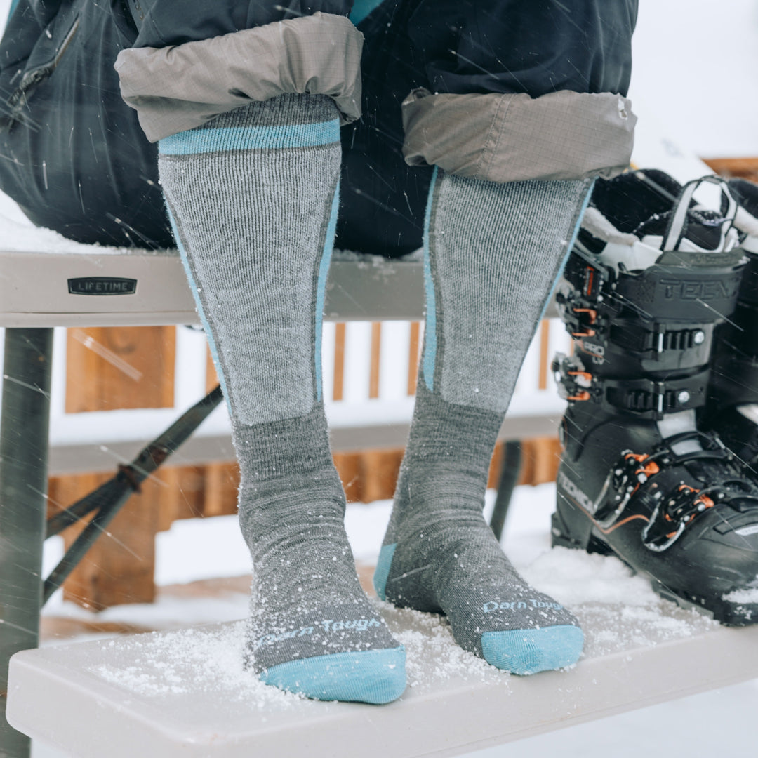 close up of models feet on picnic table wearing the 8057 Edge ski and snowboard sock in gray 