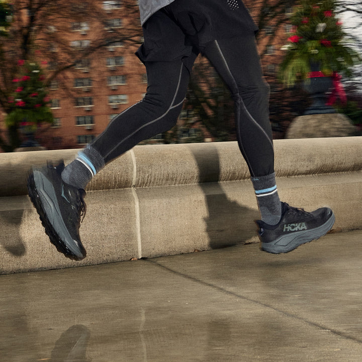 man running in city on wet sidewalk wearing black leggings and 1118 element micro crew light weight with cushion gray sock