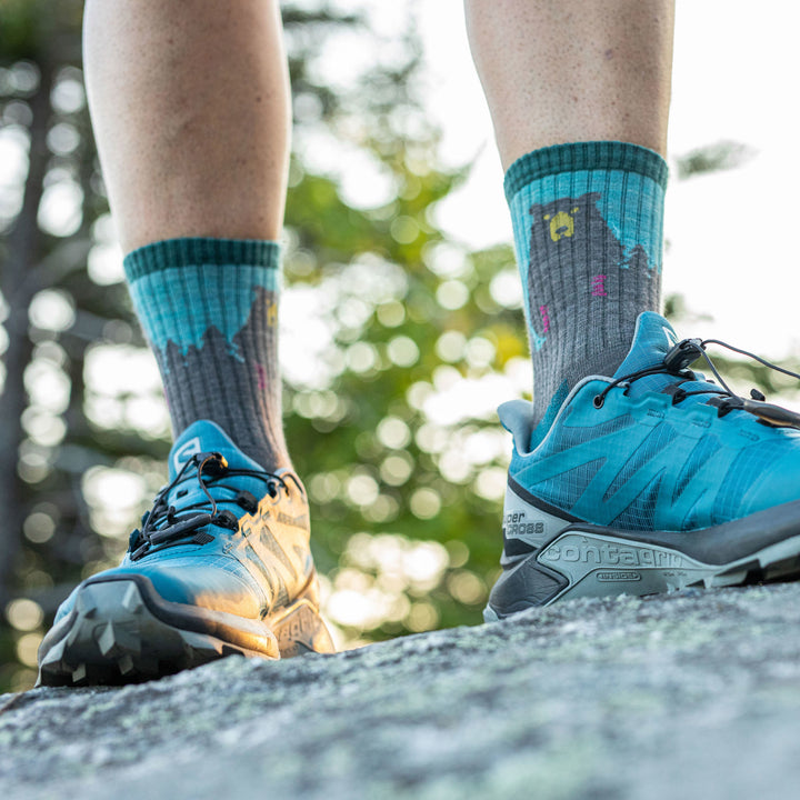 Woman standing on a rock wearing blue sneakers and Women's Bear Town Micro Crew Lightweight Hiking Socks in Aqua
