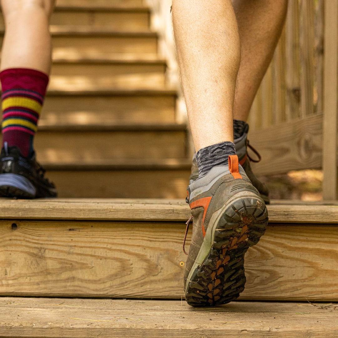 Close up shot of model walking up steps wearing the men's light hiker quarter sock in space gray