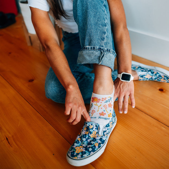 Close up shot of model sitting on a wood floor wearing the women's garden party no show hidden lifestyle sock in white