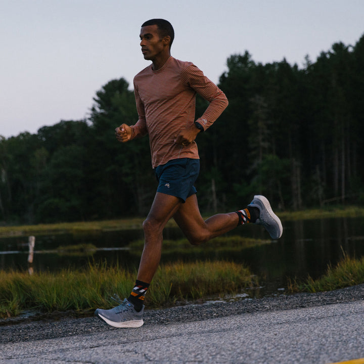 Full shot of model running on a pathway wearing the men's grit micro crew running socks in black