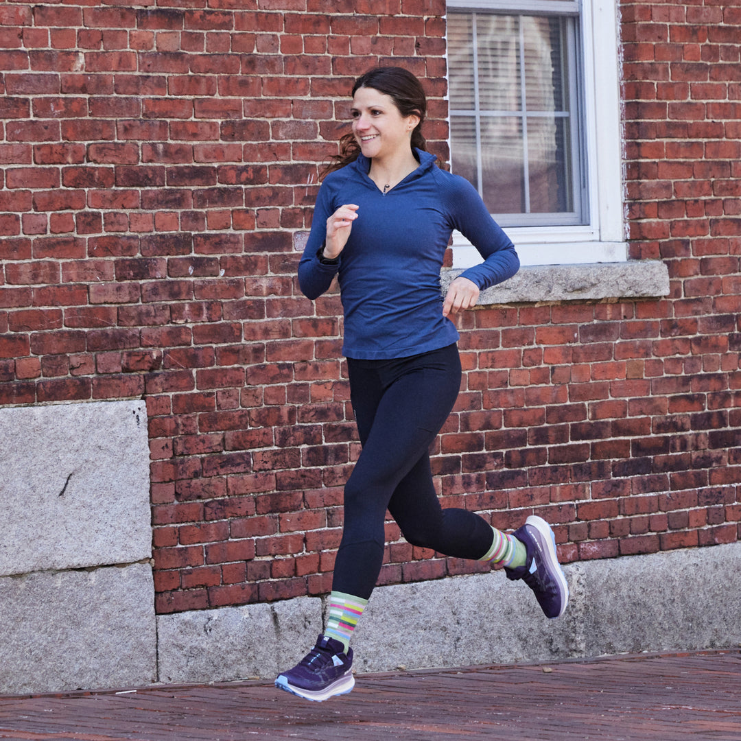Action shot of model running against brick background while wearing 1063 socks in Mint colorway