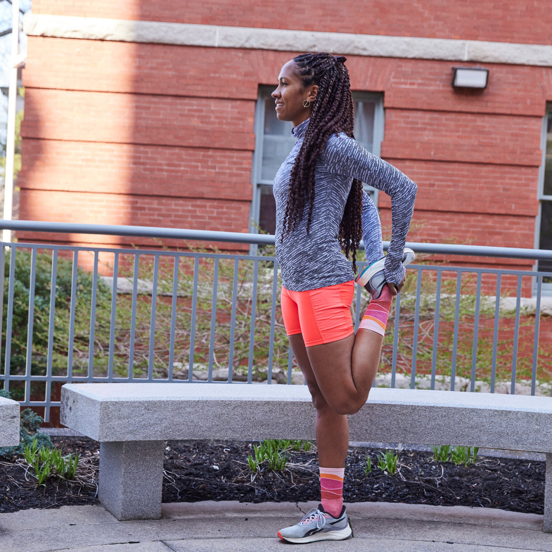 Action shot of model stretching before run wearing 1064 socks in canyon colorway 