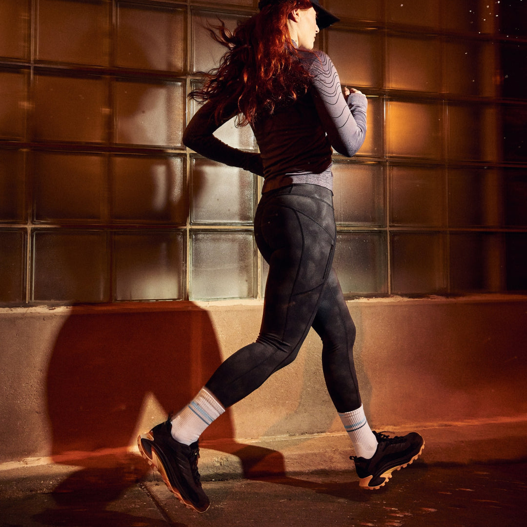 model running in front of building at night wearing 1114 element micro crew lightweight with cushion vapor white sock