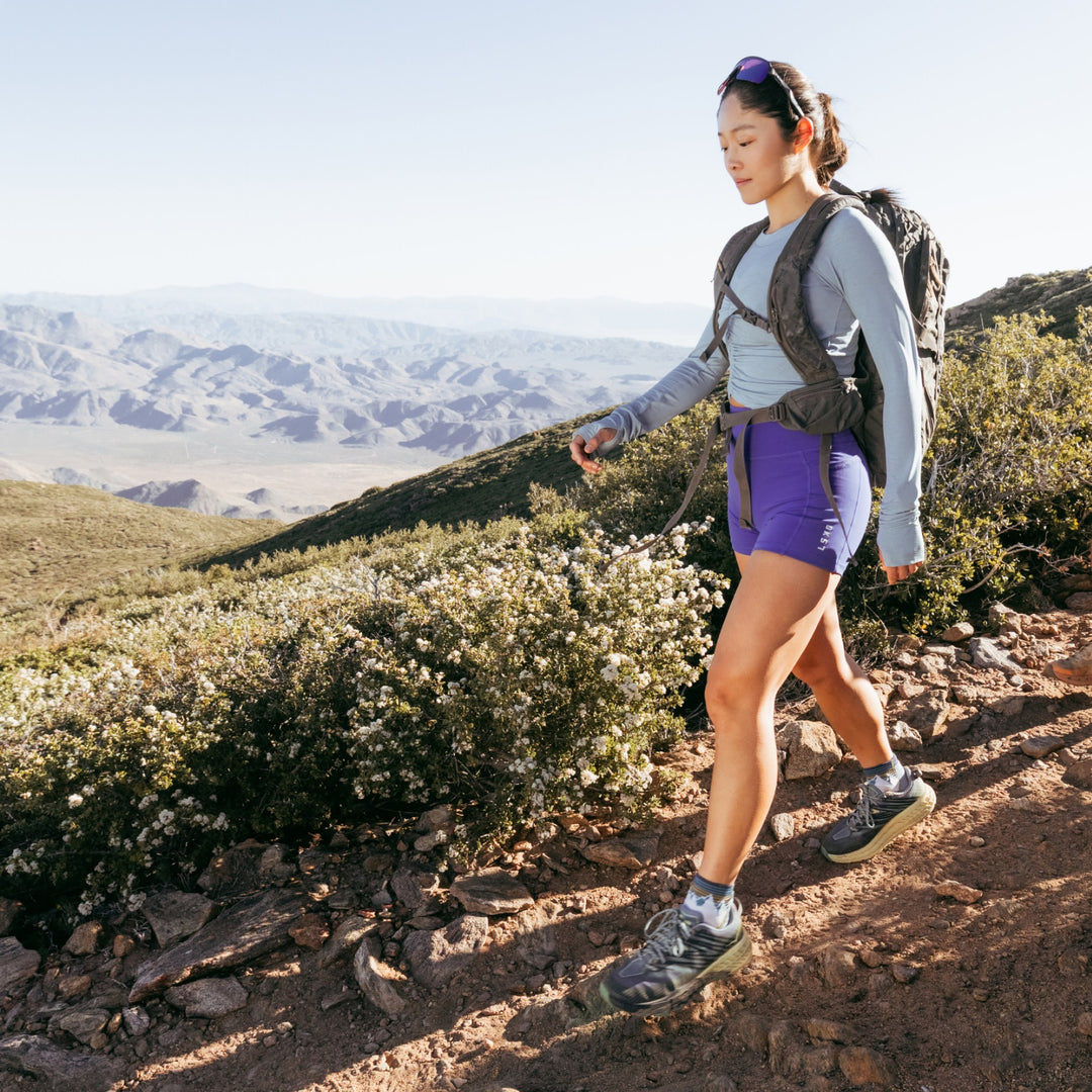 model walking on a hiking trail wearing the 1958 quarter midweight hiking sock in mountain white colorway