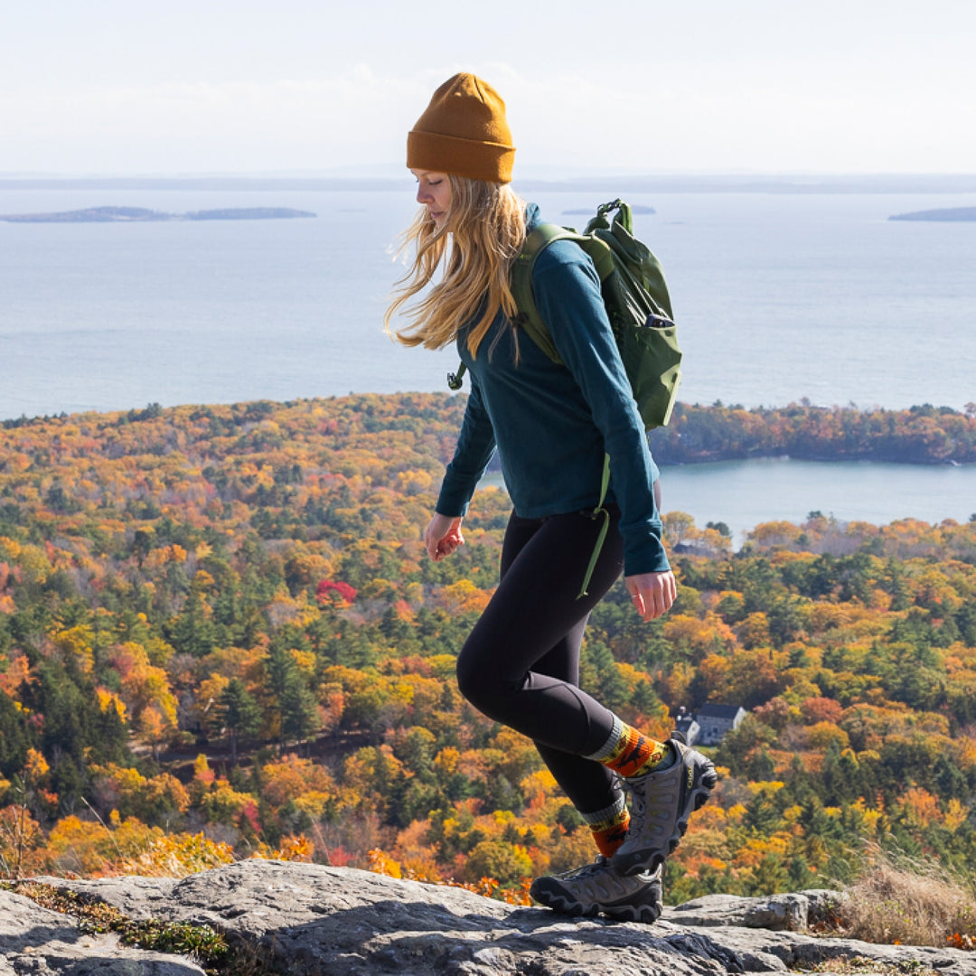woman hiking with ocean and foliage in background wearing 5017 boot midweight with cushion moose meadow sock