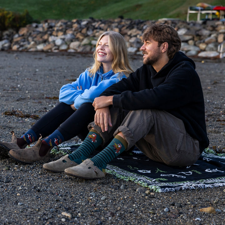 image of man and woman sitting on blanket on beach man wearing 6096 wildlife crew lightweight with cushion fox teal sock