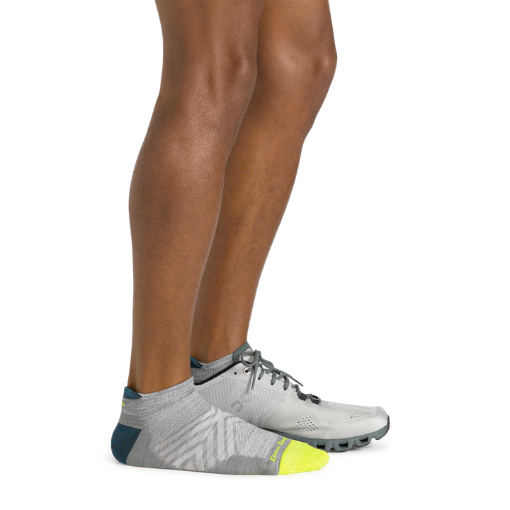 Side shot of model wearing the men's no show tab running sock in gray with a gray sneaker on his left foot