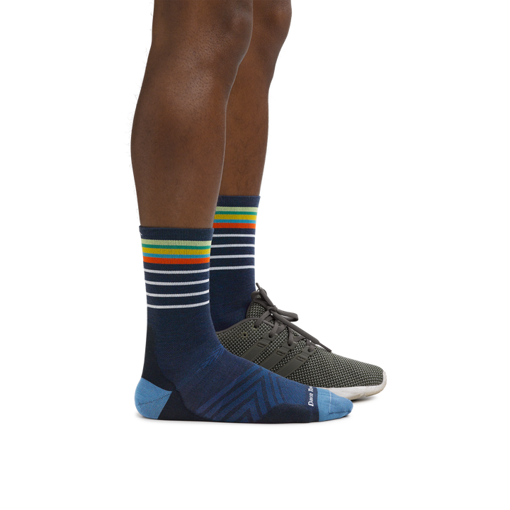 Man wearing Stride Micro Crew Ultra-Lightweight Running Socks in Eclipse with a running shoe on the foot in back