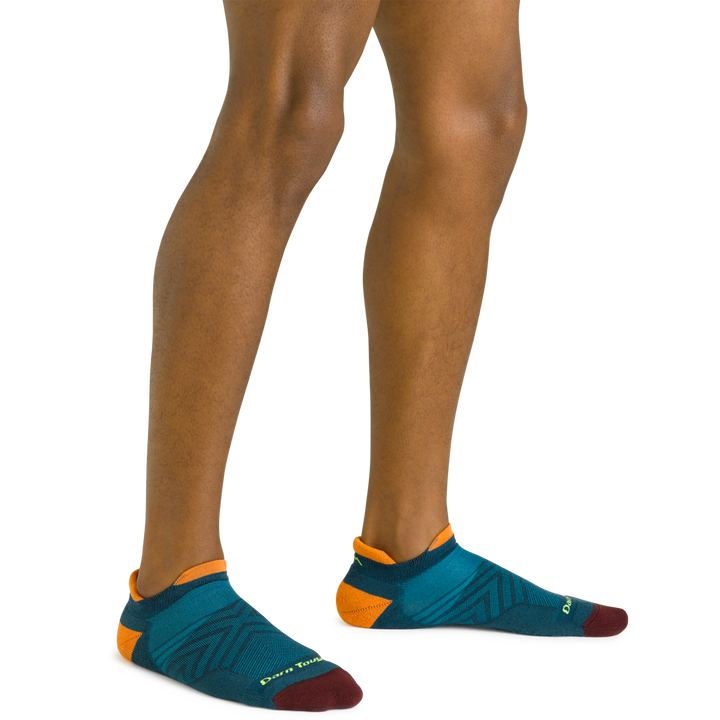 Close up shot of model wearing the men's no show tab running sock in dark teal with no shoes on