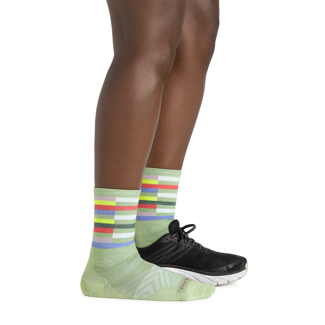 Side shot of model wearing the women's relay micro crew running sock in mint with a black shoe on her left foot