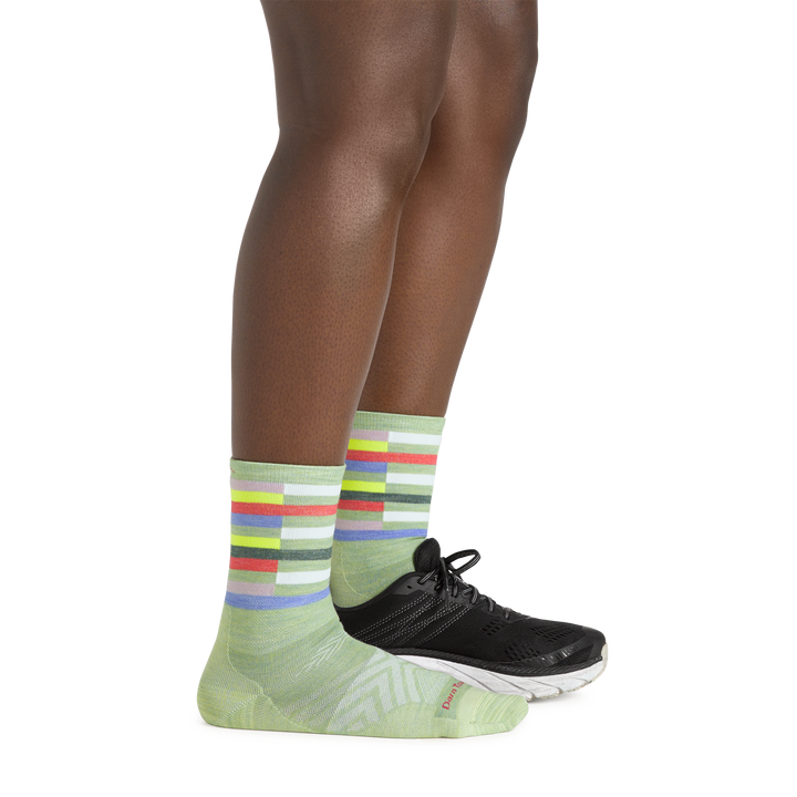 Side shot of model wearing the women's relay micro crew running sock in mint with a black shoe on her left foot