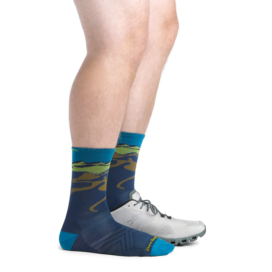On Model image of the 1065 midnight back foot with shoe on front foot featuring navy body mountain landscape on cuff 