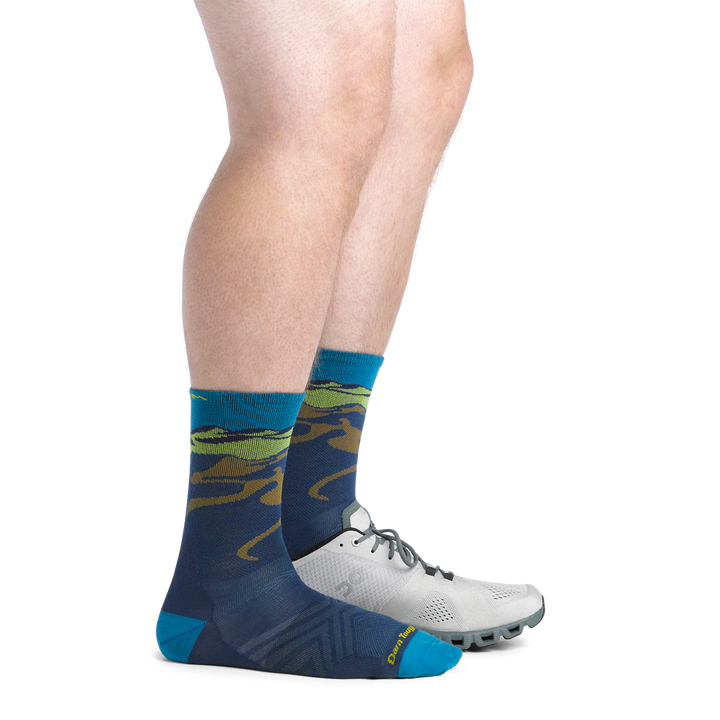 On Model image of the 1065 midnight back foot with shoe on front foot featuring navy body mountain landscape on cuff 