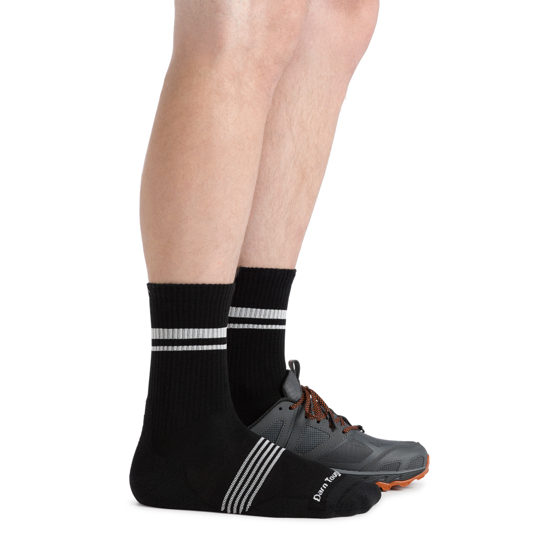 Side shot of model wearing the men's element micro crew running sock in black with a gray sneaker on his left foot