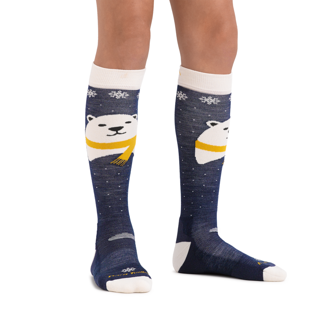 Kid standing barefoot on a white background wearing Kids Polar Bear Over the Calf Midweight Ski and Snowboard Sock