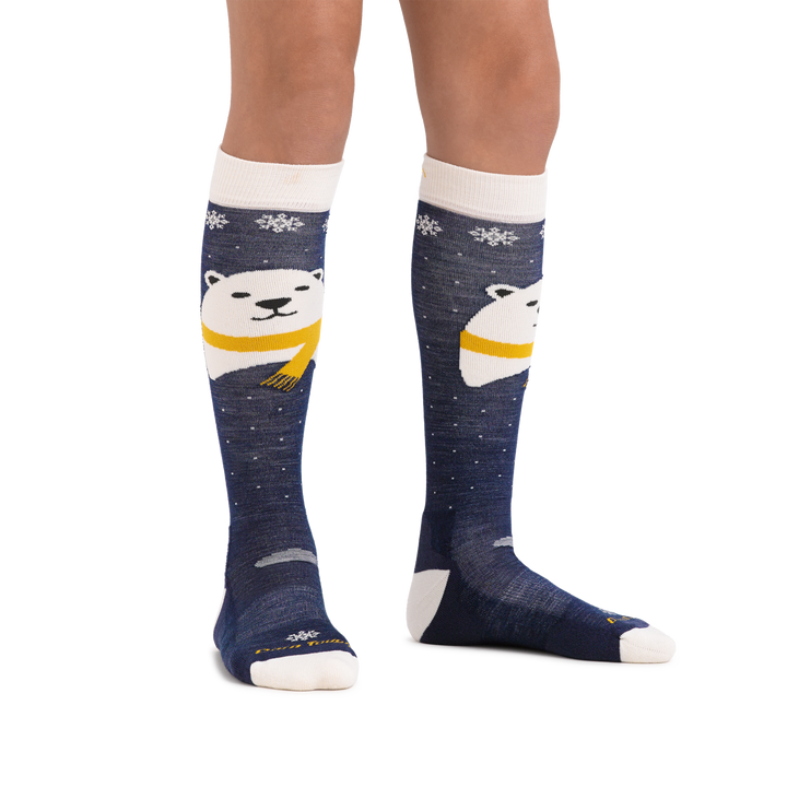 Kid standing barefoot on a white background wearing Kids Polar Bear Over the Calf Midweight Ski and Snowboard Sock