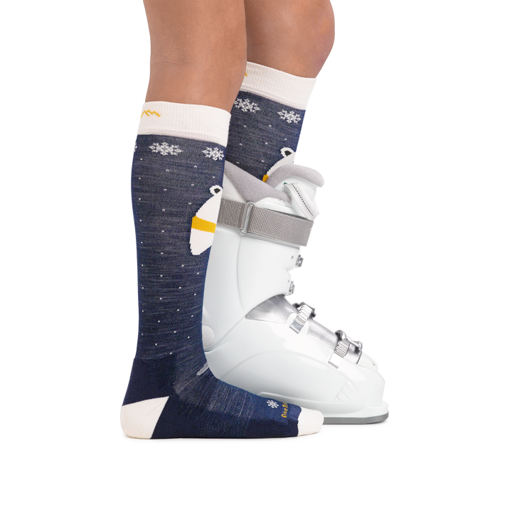 Kid wearing Kids Polar Bear Over the Calf Midweight Ski & Snowboard Sock in Blue with rear foot also in a ski boot