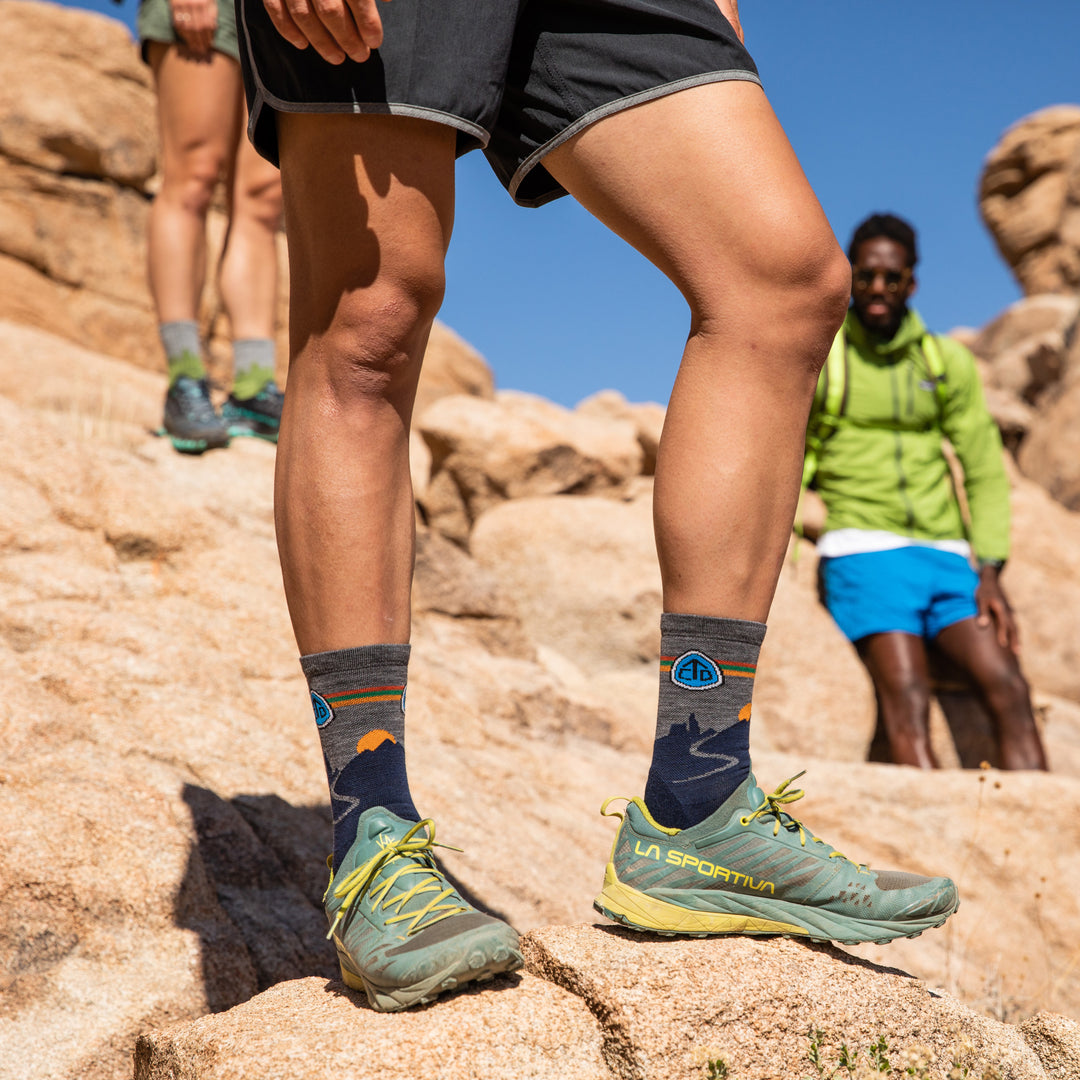 Side shot of model standing on rocks in Joshua Tree National Park weaing the CDT micro crew hiking sock in eclipse blue