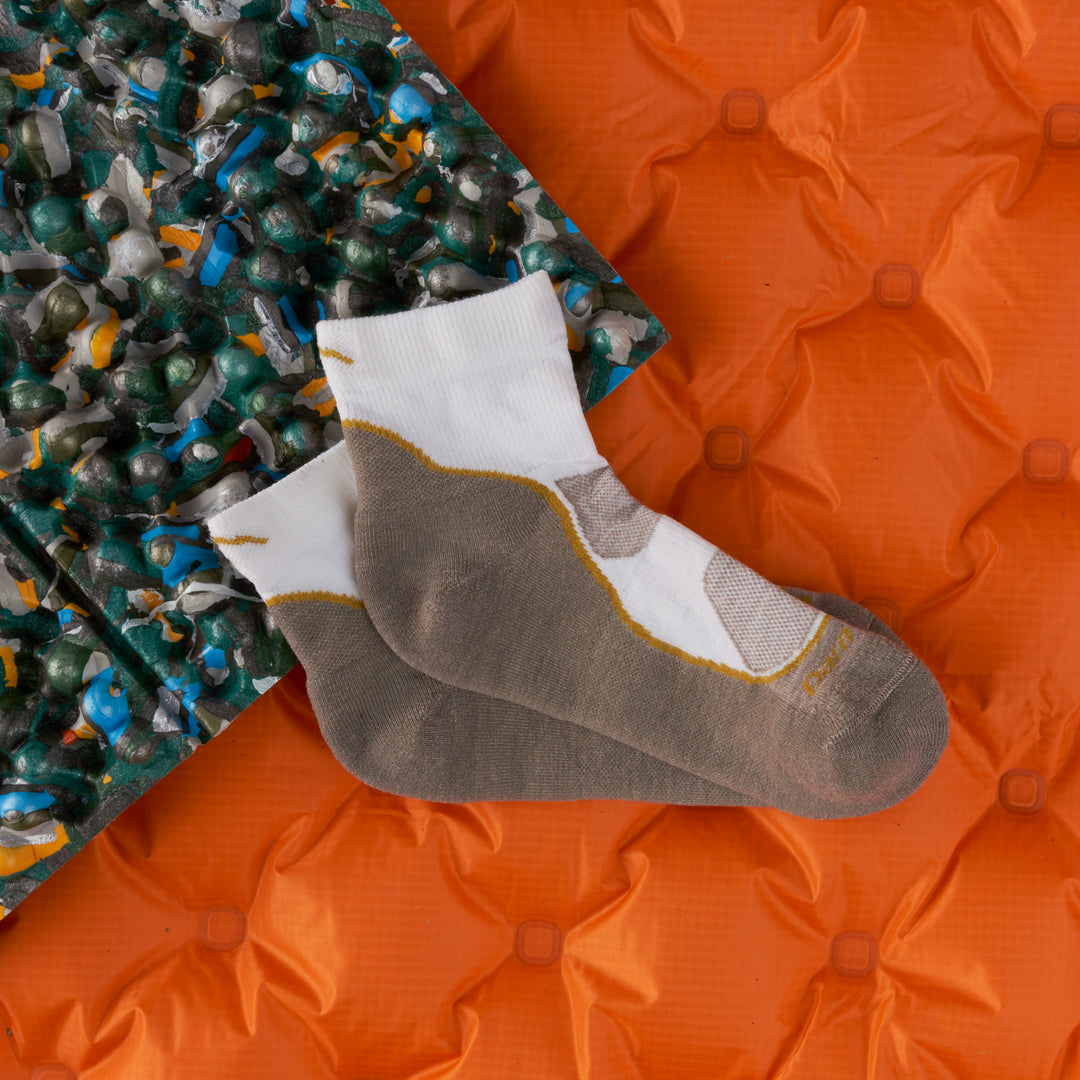 Women's lightweight quarter hiker in oat milk laying on orange sleeping bag and sleeping pad 