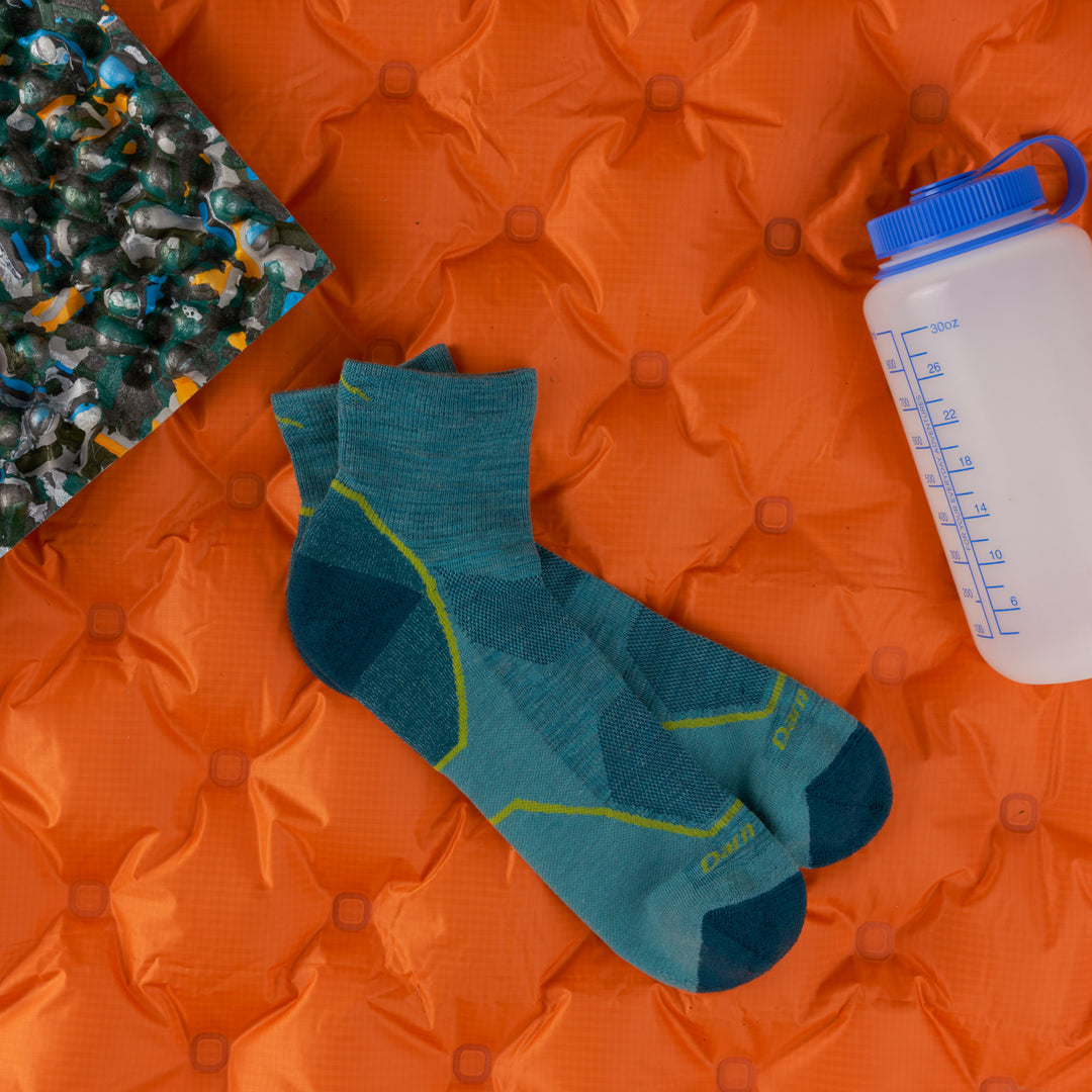 men's lightweight quarter hiker in aqua on an orange sleeping bag with waterbottle 