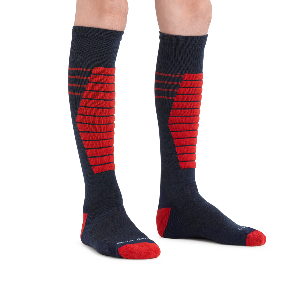 Kid standing barefoot wearing Edge Over the Calf Midweight Ski & Snowboard socks in Eclipse