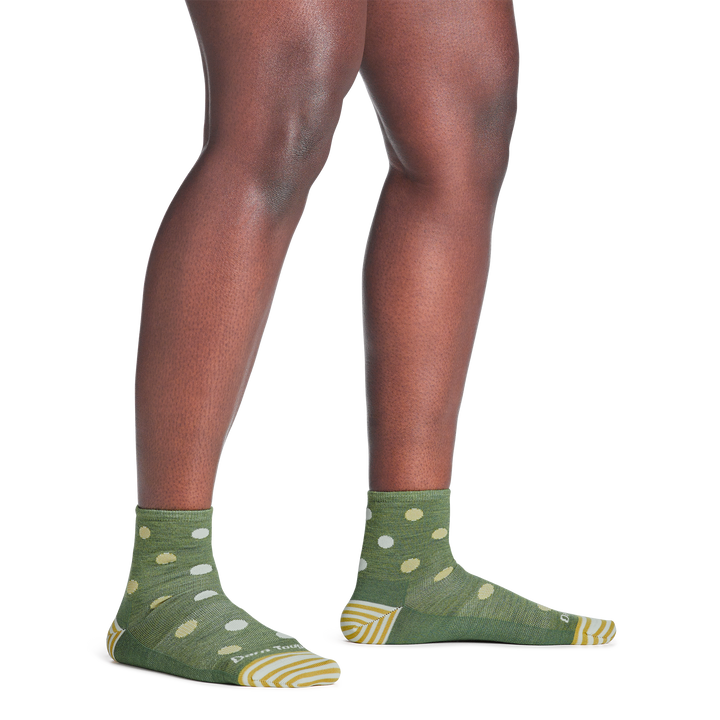 model standing barefoot wearing the 6103 dottie shorty lifestyle sock in willow green colorway
