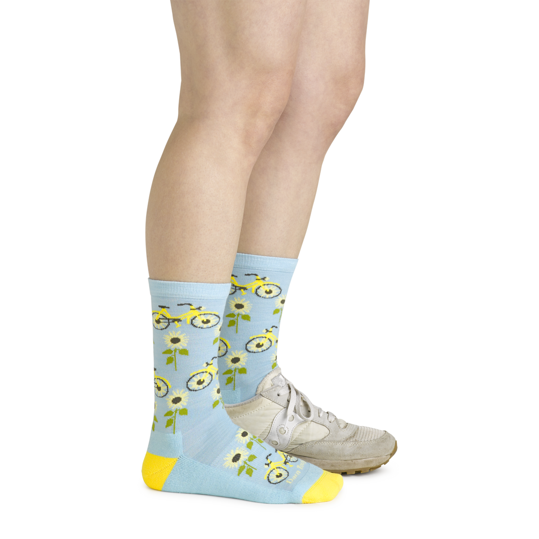 Model wearing the women's sun pedal crew lifestyle socks in glacier blue with a white sneaker on her left foot