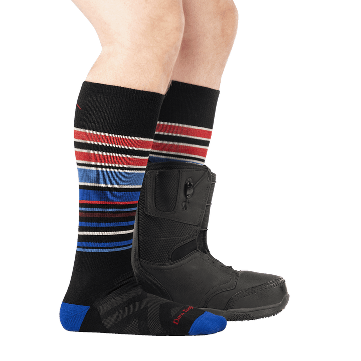 model wearing snowboard boot on back foot and 8017 black midweight OTC ski and snowboard sock side profile
