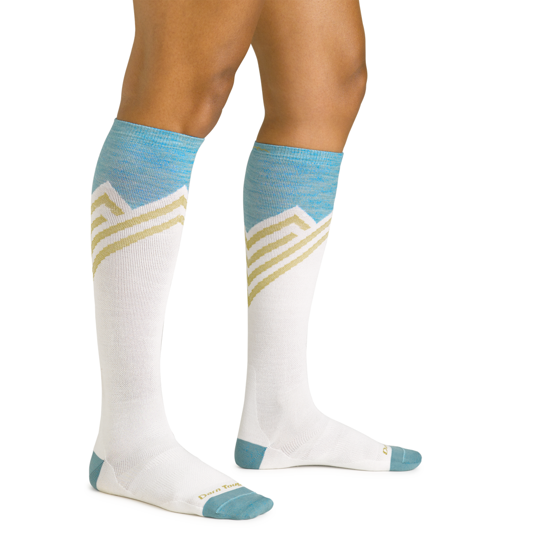 Close up studio shot of model wearing women's peaks over-the-calf lightweight ski & snowboard sock in white