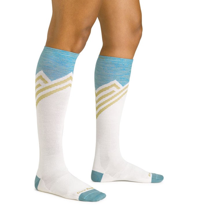 Close up studio shot of model wearing women's peaks over-the-calf lightweight ski & snowboard sock in white