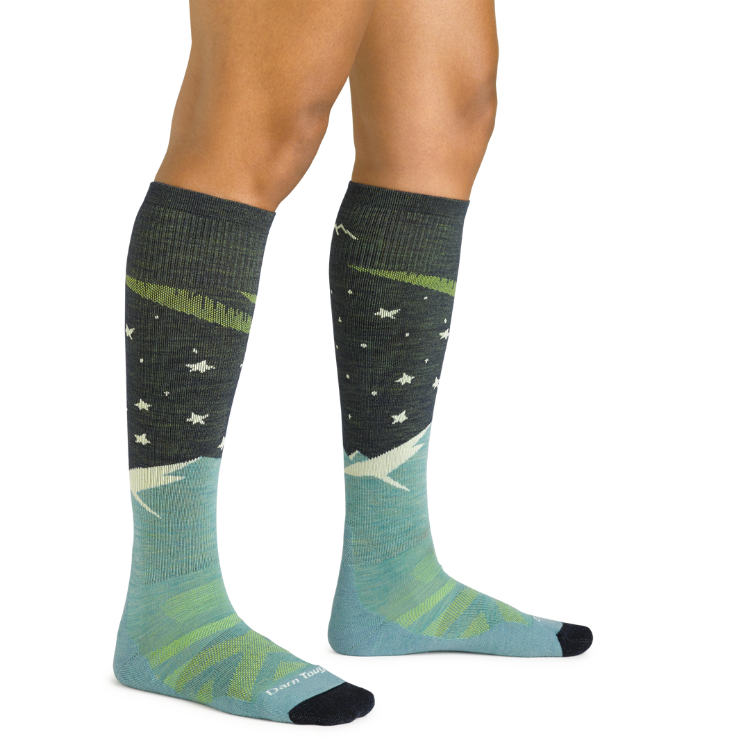 Close up studio shot of model wearing women's aurora over-the-calf lightweight ski & snowboard sock in aqua