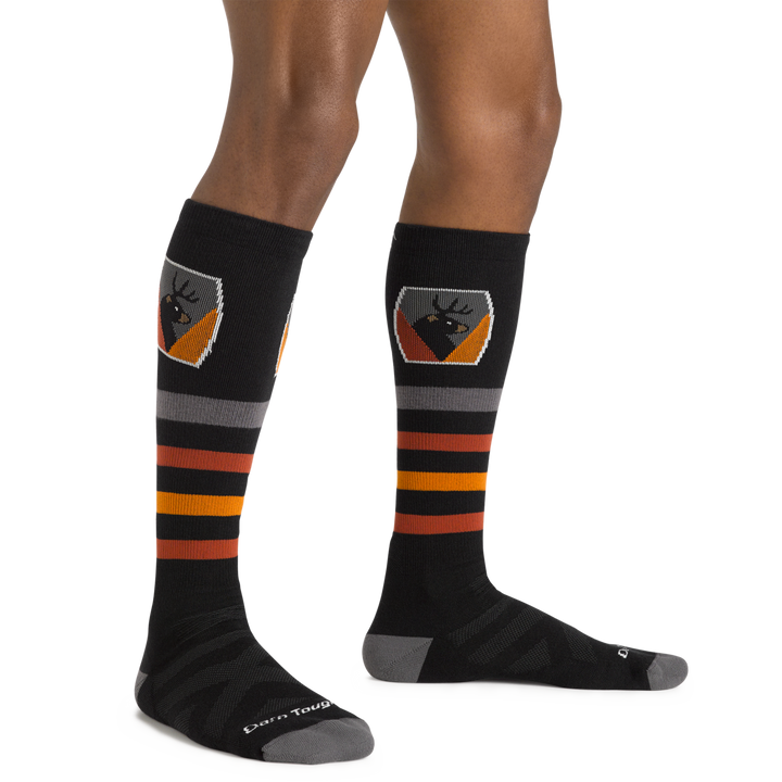 Man standing barefoot wearing Beer Badge Over the Calf Ski & Snowboard socks in black