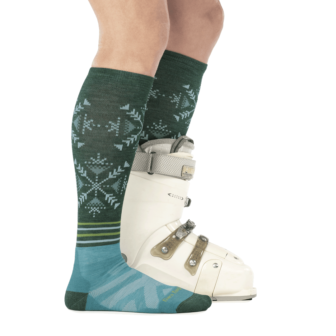 model wearing ski boot on back foot and 8060 OTC ski sock in juniper side profile on front foot