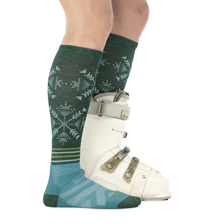 model wearing ski boot on back foot and 8060 OTC ski sock in juniper side profile on front foot